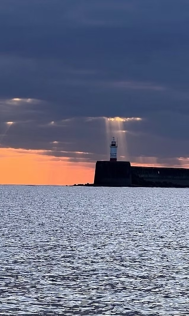 Image of lighthouse with the sunlight showing through the clouds